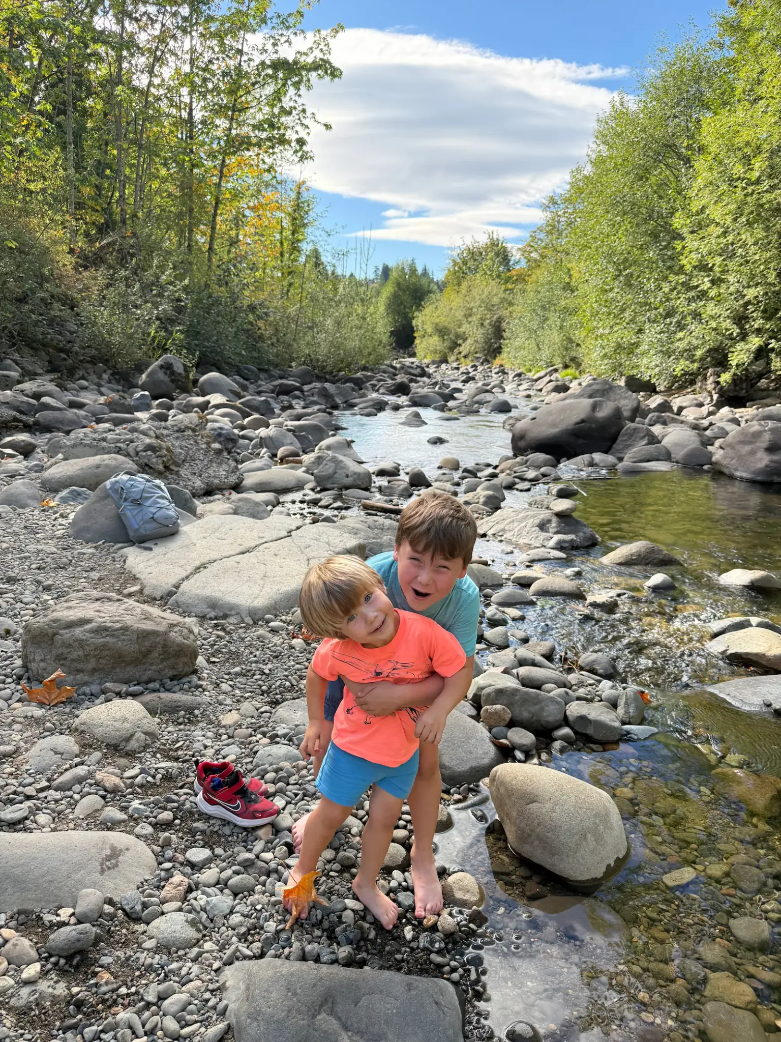 Two children playing among rocks along the river near George Smallwood Park